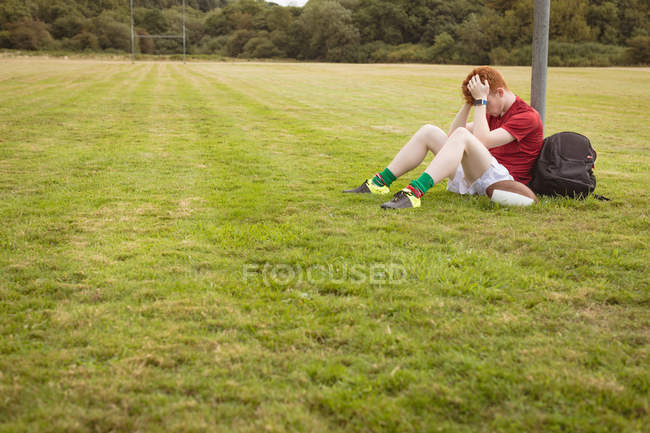 Jogador de futebol preocupado sentado no campo — Fotografia de Stock