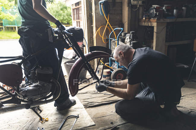 Mechanic repairing motorbike in repair garage — Stock Photo