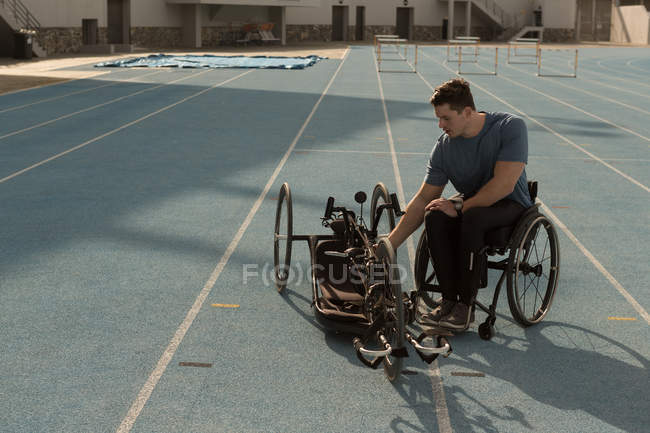 Atleta disabile maschile con sedia a rotelle su una pista da corsa — Foto stock