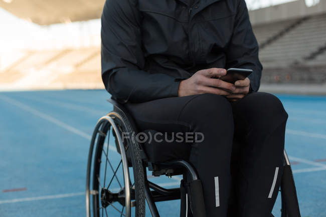 Sezione centrale dell'atleta disabile che utilizza il telefono cellulare presso la sede sportiva — Foto stock