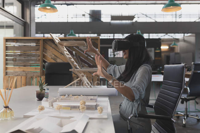 Female executive using virtual reality headset at table in office — Stock Photo