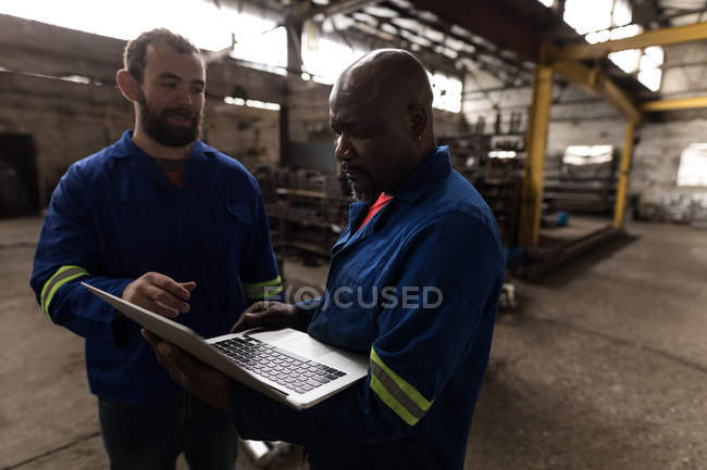 Zwei Schmied diskutieren über Laptop in Werkstatt — Stockfoto