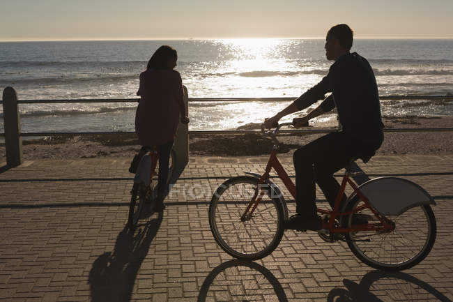 Pareja de bicicletas en el paseo marítimo cerca de la playa - foto de stock