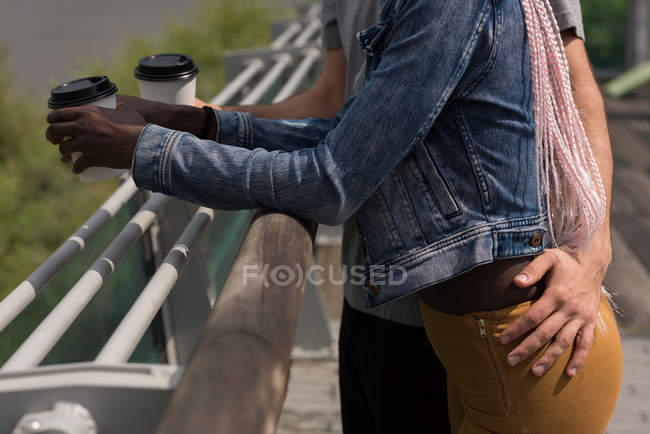 Середина пари, що стоїть з кавою біля перил — стокове фото