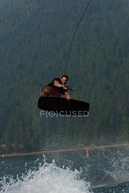 Молодий чоловік стрибає над водою під час пробудження в річці — стокове фото