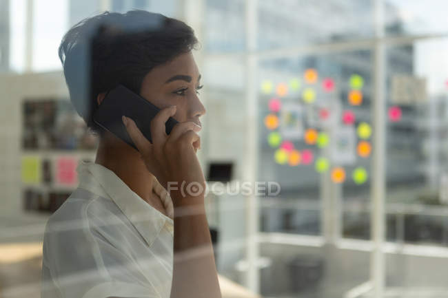Вид сбоку на бизнес-руководителя, говорящего по мобильному телефону в офисе . — стоковое фото