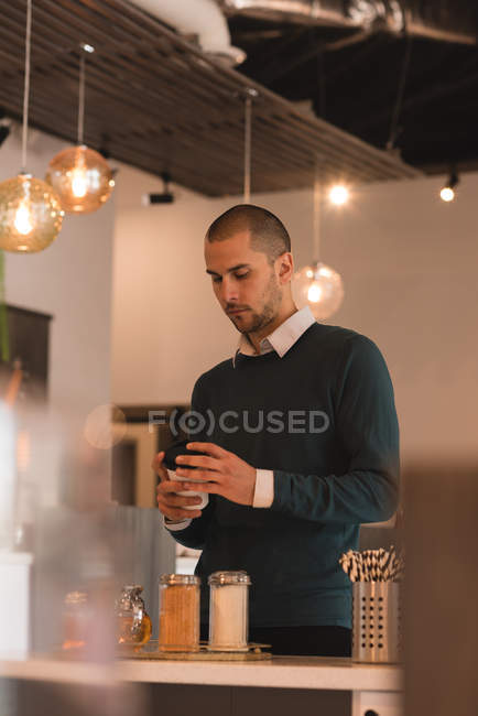 Homem olhando xícara de café no interior do café — Fotografia de Stock
