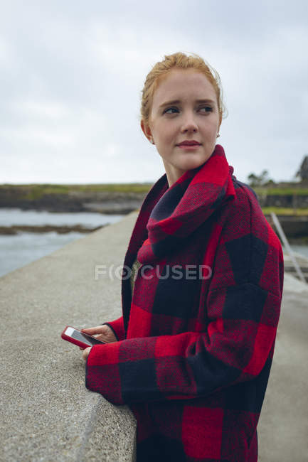 Mulher ruiva usando telefone celular na praia . — Fotografia de Stock