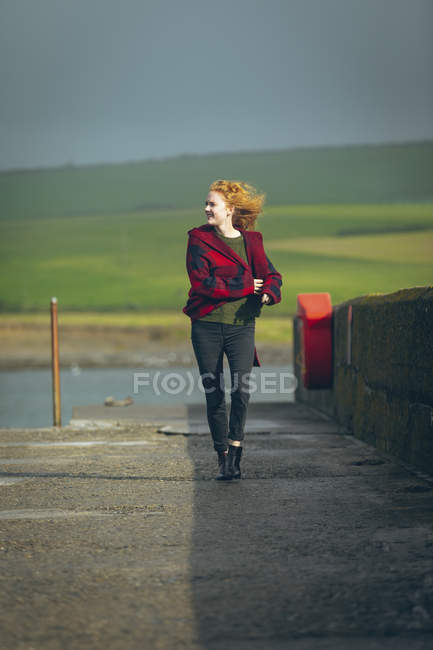 Щаслива руда жінка ходить на березі океану . — стокове фото