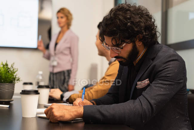 Male executive writing on notepad in office — Stock Photo