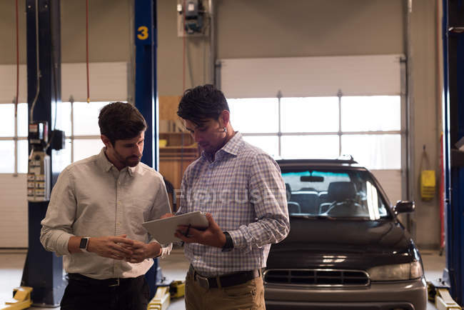 Two craftsmen discussing over digital tablet in workshop — Stock Photo