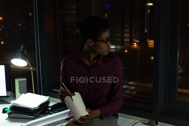 Executivo feminino ter comida no escritório à noite — Fotografia de Stock