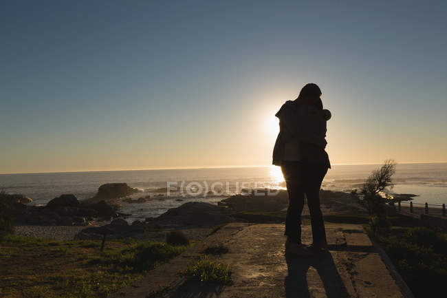 Silhouette eines Paares, das sich am Strand bei Sonnenuntergang umarmt — Stockfoto