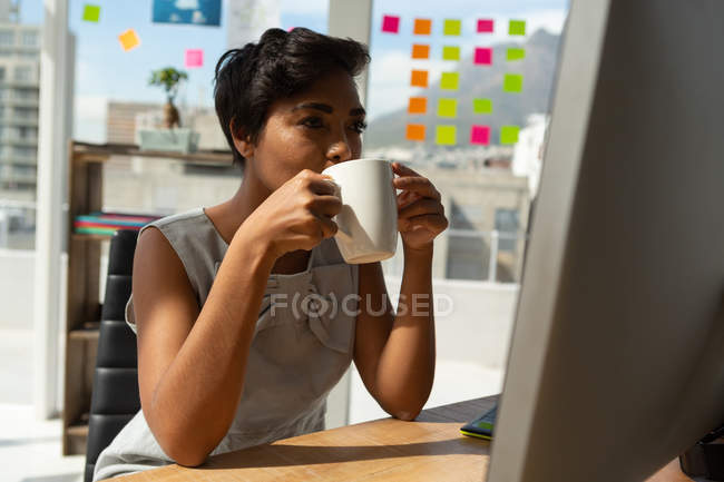 Female business executive having coffee while working in office. — Stock Photo