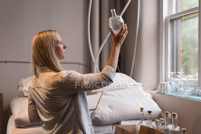 Beautiful female worker examining bottles in factory — Stock Photo