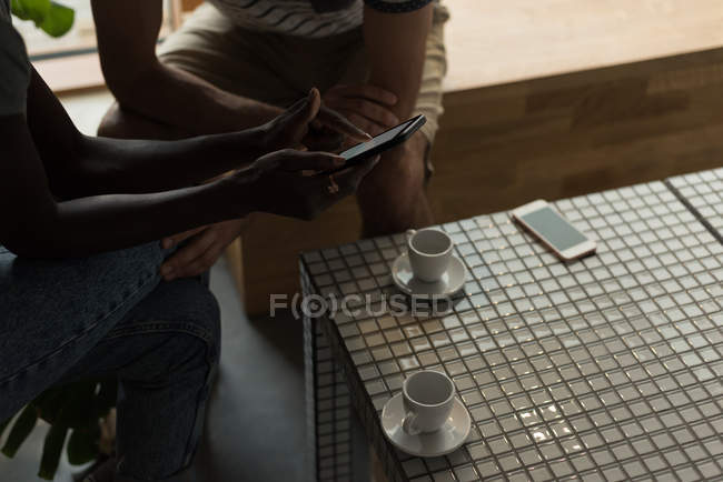 Primer plano de la pareja usando el teléfono móvil en la cafetería - foto de stock