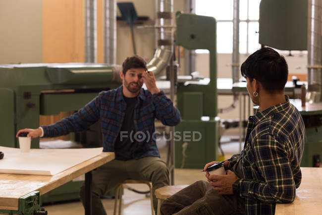 Dois artesãos interagindo uns com os outros na oficina — Fotografia de Stock