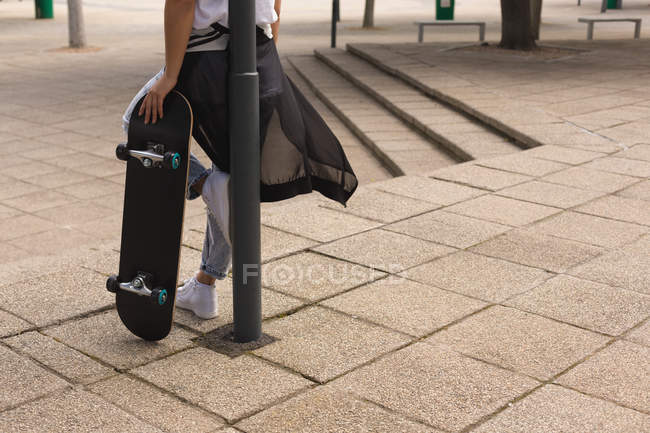 Низька секція жіночого скейтбордера, що стоїть зі скейтбордом — стокове фото
