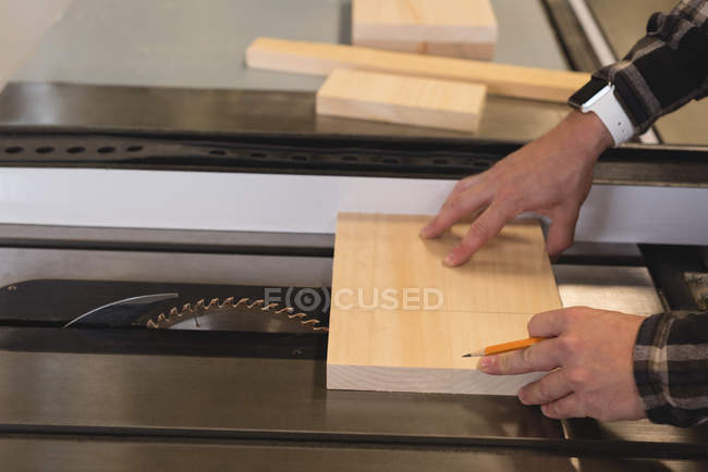 Крупный план мастера, измеряющего деревянную доску в мастерской — стоковое фото