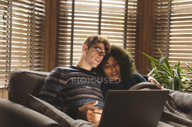 Coppia utilizzando il computer portatile in soggiorno a casa — Foto stock