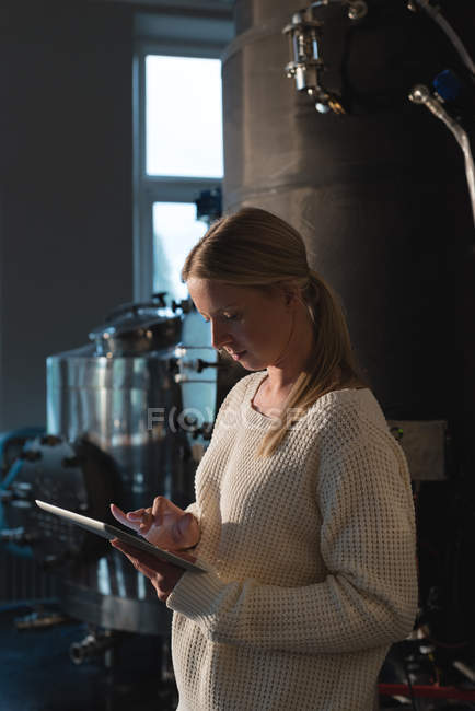 Блондинка-жіночий працівник використовує цифровий планшет на заводі пивоваріння — стокове фото