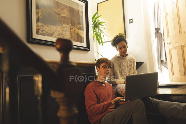 Pareja interactuando entre sí mientras se utiliza el ordenador portátil en casa - foto de stock