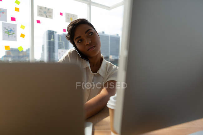 Business executive talking on mobile phone while working on desk at office. — Stock Photo