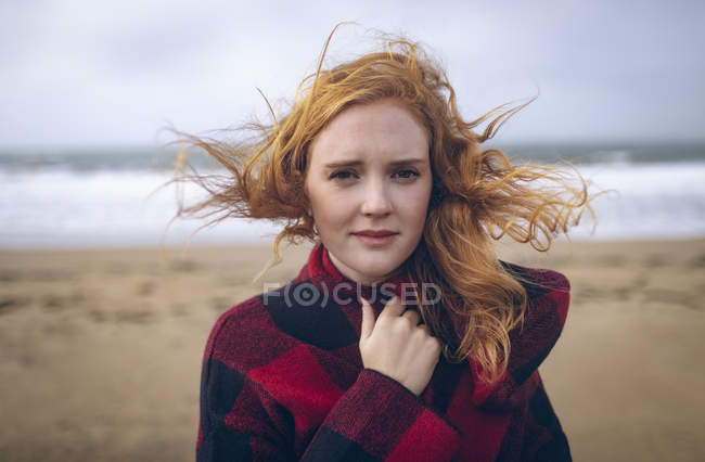 Retrato de mujer pelirroja de pie en la playa . - foto de stock