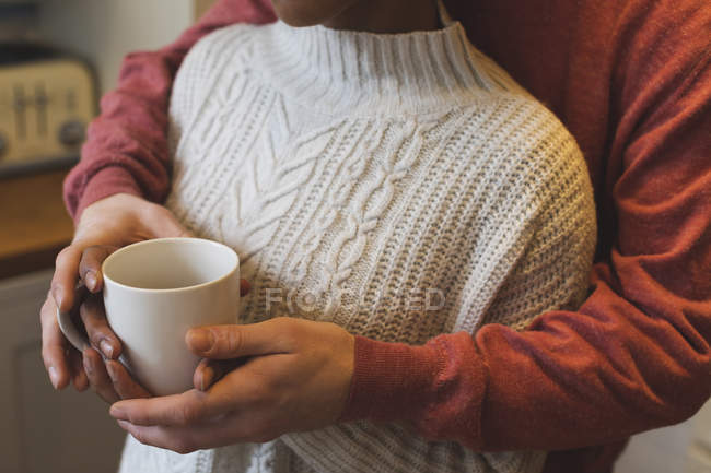 Seção média do casal segurando caneca de café em casa — Fotografia de Stock