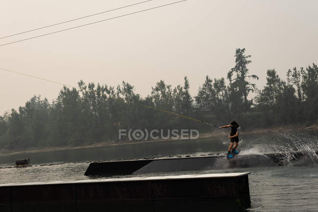Giovane atleta wakeboarding nel fiume al tramonto — Foto stock