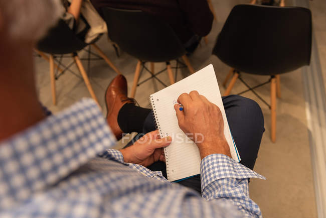 Male executive writing on notepad in office — Stock Photo