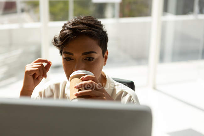 Представительница женского бизнеса пьет кофе во время работы в офисе . — стоковое фото