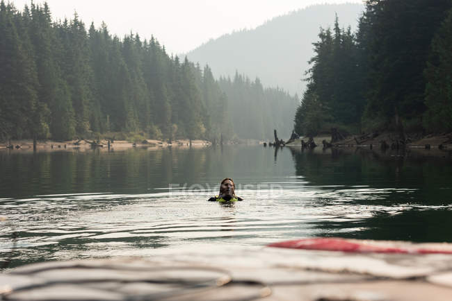 Взрослый мужчина плавает в воде после падения с вейкборда в реке — стоковое фото