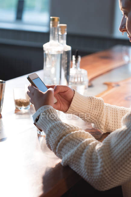 Крупним планом жіночі руки використовують мобільний телефон за барним столом — стокове фото