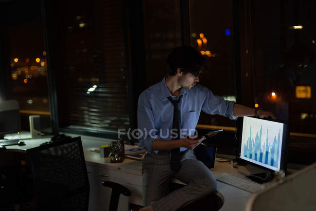 Hombre ejecutivo trabajando en el escritorio en la oficina por la noche - foto de stock