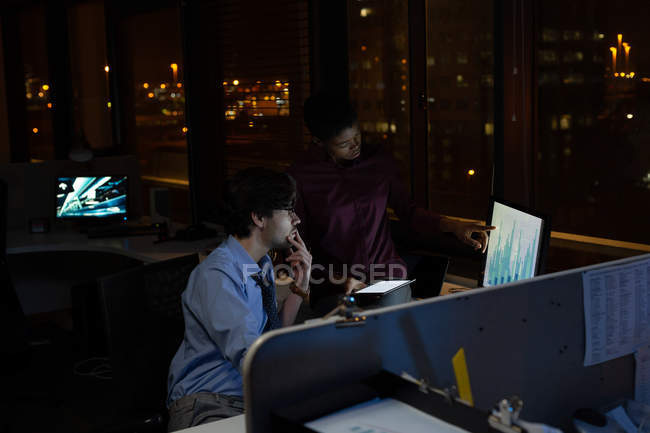 Ejecutivos trabajando hasta tarde en el escritorio en la oficina por la noche - foto de stock