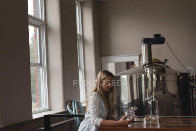 Hermosa trabajadora examinando botella en fábrica - foto de stock