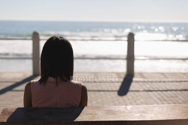 Rear view of woman sitting on promenade near beach — Stock Photo