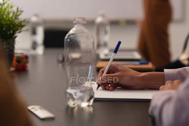 Vista cortada da escrita executiva feminina no bloco de notas no escritório — Fotografia de Stock