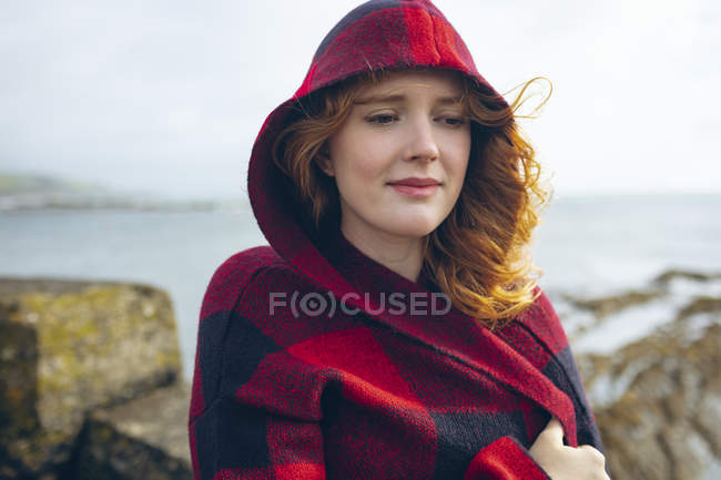 Nachdenkliche rothaarige Frau steht am Strand. — Stockfoto