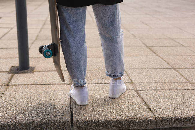 Unterteil einer Skateboarderin steht mit Skateboard — Stockfoto