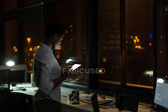 Ejecutiva femenina usando tableta digital en la oficina por la noche - foto de stock