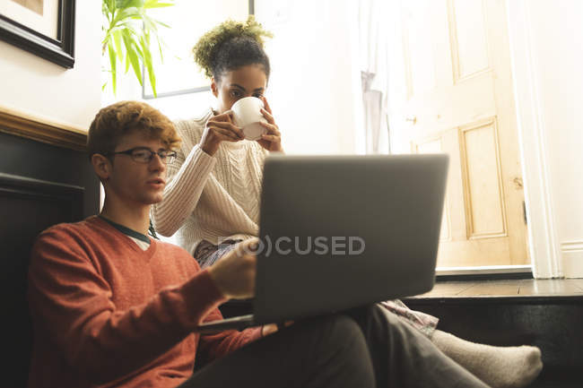 Casal tomando café ao usar laptop em casa — Fotografia de Stock