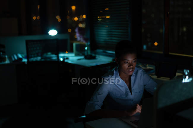 Mujer ejecutiva trabajando en el escritorio en la oficina por la noche - foto de stock