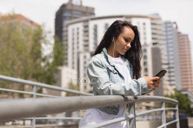 Beautiful young brunette using mobile phone in city — Stock Photo