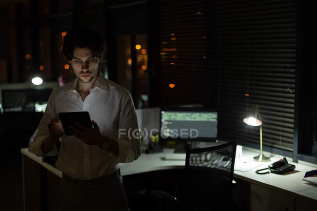 Uomo esecutivo utilizzando tablet digitale in ufficio di notte — Foto stock