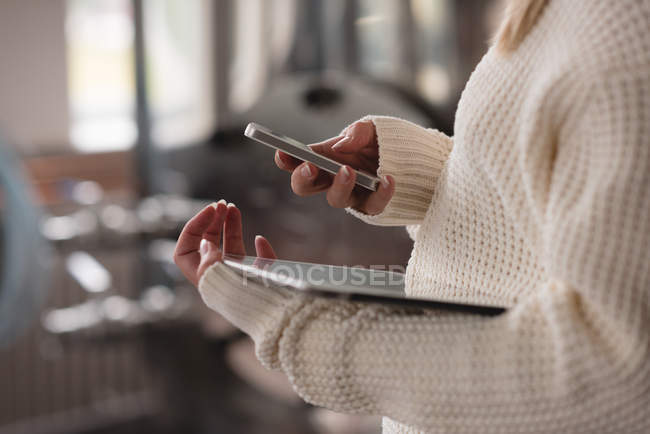 Sección media de la mujer que utiliza el teléfono móvil y la tableta digital - foto de stock