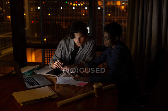 Dirigenti che discutono su tablet digitale in ufficio di notte — Foto stock
