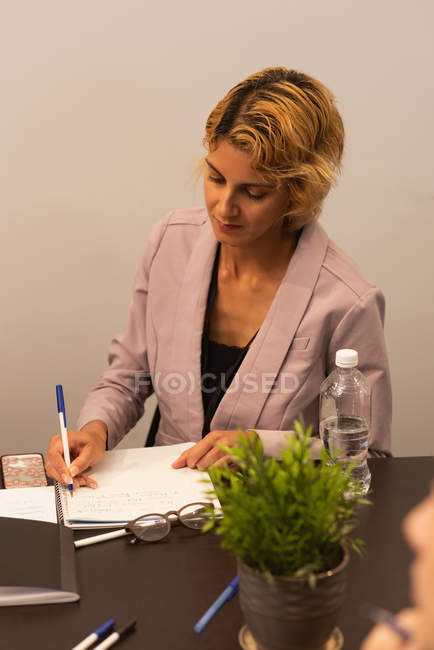 Escrita executiva feminina no bloco de notas no escritório — Fotografia de Stock