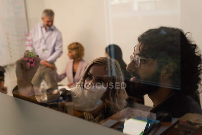 Руководители, пишущие на стеклянной стене в офисе — стоковое фото
